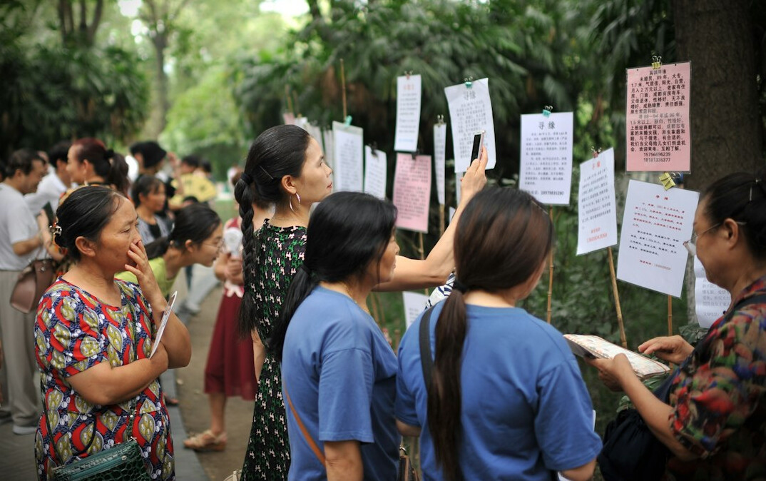Group of neighbors looking at printed photographs pinned on a community board