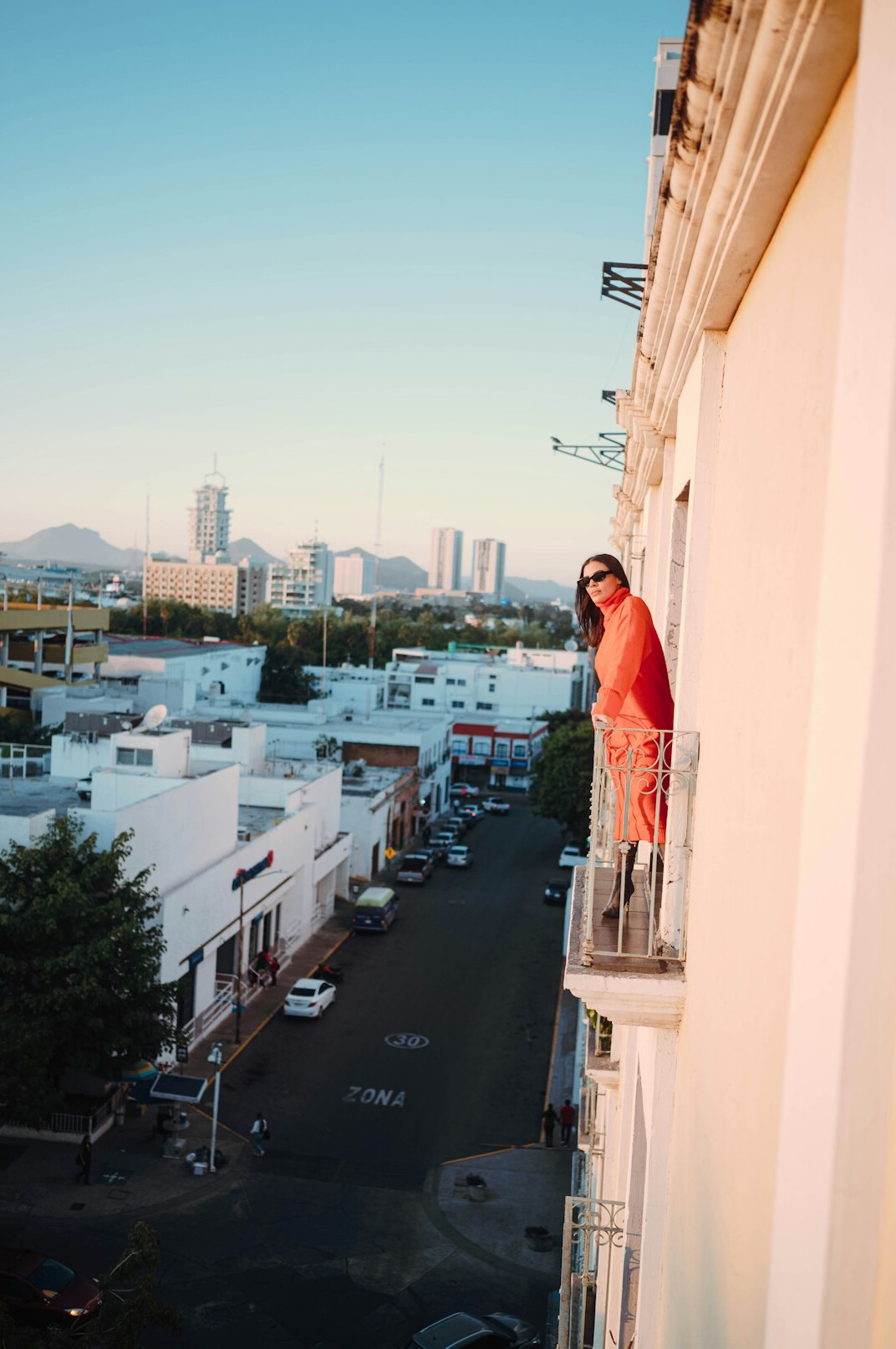 Elderly Chilean woman looking out from her balcony over the city